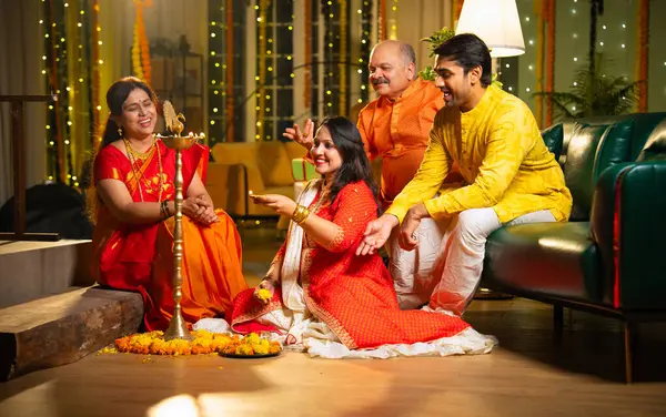 Diwali 'de evde samai diya aydınlatması, Hintli dört kişilik Hint ailesi sari, baba, genç kız ve koca Hindu festivalini neşe ve gelenekle kutlarken birlikte gülümsüyor.