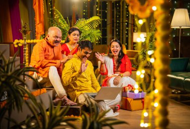 Hindu Diwali festivalini kutlayan dört çocuklu Hintli aile, dizüstü bilgisayarlı video görüşmelerine katılıyor. Ev içi yemek masasında şeker ve ışıklarla kutluyorlar.