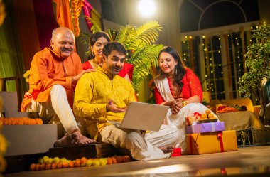 Hindu Diwali festivalini kutlayan dört çocuklu Hintli aile, dizüstü bilgisayarlı video görüşmelerine katılıyor. Ev içi yemek masasında şeker ve ışıklarla kutluyorlar.