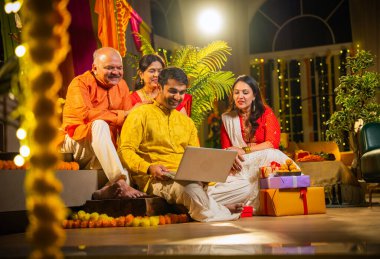 Hindu Diwali festivalini kutlayan dört çocuklu Hintli aile, dizüstü bilgisayarlı video görüşmelerine katılıyor. Ev içi yemek masasında şeker ve ışıklarla kutluyorlar.