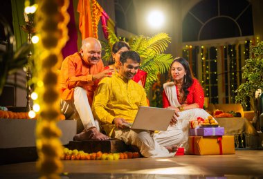 Hindu Diwali festivalini kutlayan dört çocuklu Hintli aile, dizüstü bilgisayarlı video görüşmelerine katılıyor. Ev içi yemek masasında şeker ve ışıklarla kutluyorlar.