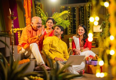 Hindu Diwali festivalini kutlayan dört çocuklu Hintli aile, dizüstü bilgisayarlı video görüşmelerine katılıyor. Ev içi yemek masasında şeker ve ışıklarla kutluyorlar.