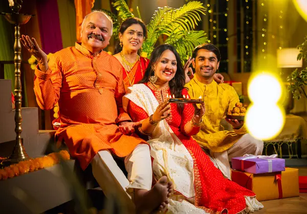 Kameraya mutlu Diwali 'ler, genç kızı olan Hintli aile, sari giyen yaşlı anne, geleneksel giyimli baba kapalı merdivenlerde oturan, mutlu bir şekilde gülümseyen bir koca.
