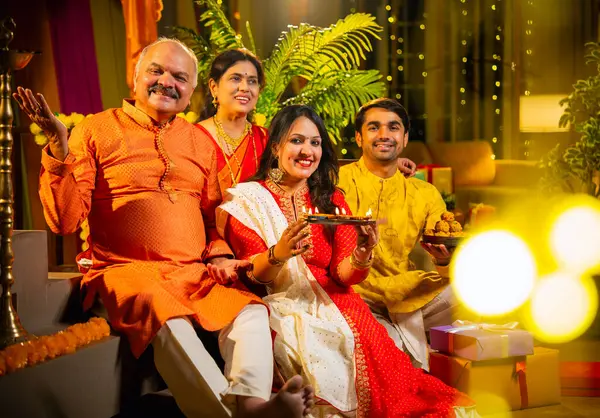 Kameraya mutlu Diwali 'ler, genç kızı olan Hintli aile, sari giyen yaşlı anne, geleneksel giyimli baba kapalı merdivenlerde oturan, mutlu bir şekilde gülümseyen bir koca.
