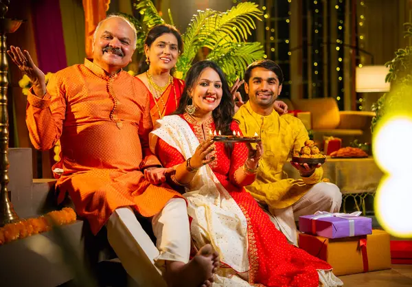Kameraya mutlu Diwali 'ler, genç kızı olan Hintli aile, sari giyen yaşlı anne, geleneksel giyimli baba kapalı merdivenlerde oturan, mutlu bir şekilde gülümseyen bir koca.