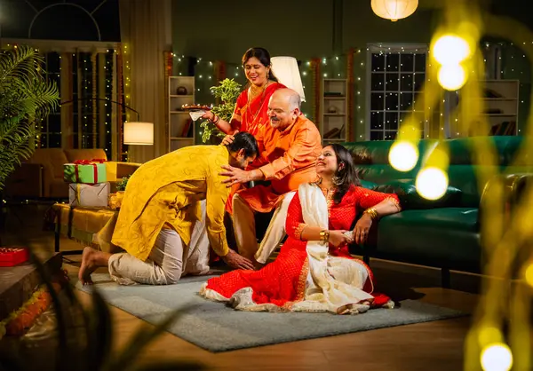 Oğul, anne ve babasından Diwali duası almak için şenlikli bir evde anne, baba ve genç kız oğulla sıcak bir jestle selamlaştıktan sonra televizyonda komik bir program izliyorlar.