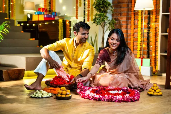 Geleneksel etnik kıyafetli Hintli çift, çiçekli çelenkler, ışıklar ve şenlikli neşeyle süslenmiş, neşeli havasıyla Diwali gecesinin tadını çıkarıyor.