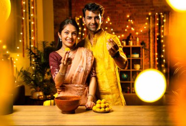 Hint çifti Diwali 'de süslü mutfakta laddu yapıyor. Işıklar ve çiçek çelenkleriyle dolu, neşe içinde geleneksel laddoo' yu hazırlıyor, sergiliyor ya da birlikte yiyor.