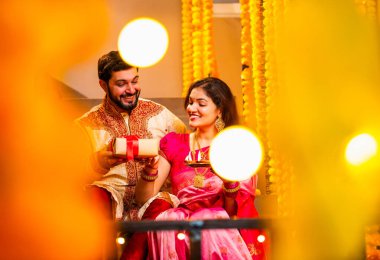 Koca, Karısına Diwali Hediyesi Veriyor, Geleneksel Giysilerle Dekoratif Merdivenlerde oturan Hintli Çift, Diya Thali 'yi tutuyor, Diwali Gecesinde Gülümseyen ve Karşılıklı Sürpriz Hediye Veriyor