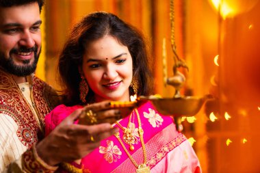 Diwali 'de Pirinç Yağı Samai, Geleneksel Kurta' da Hintli Genç Adam ve Kadın Gülümseyen Sari Dekoratif Festival Lambası Gece Samimi Etnik Ev Ayarları 'nda