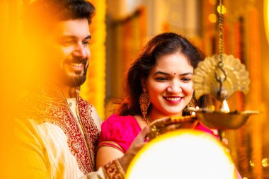 Diwali 'de Pirinç Yağı Samai, Geleneksel Kurta' da Hintli Genç Adam ve Kadın Gülümseyen Sari Dekoratif Festival Lambası Gece Samimi Etnik Ev Ayarları 'nda