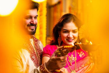 Diwali 'de Pirinç Yağı Samai, Geleneksel Kurta' da Hintli Genç Adam ve Kadın Gülümseyen Sari Dekoratif Festival Lambası Gece Samimi Etnik Ev Ayarları 'nda