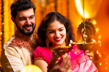 Diwali 'de Pirinç Yağı Samai, Geleneksel Kurta' da Hintli Genç Adam ve Kadın Gülümseyen Sari Dekoratif Festival Lambası Gece Samimi Etnik Ev Ayarları 'nda