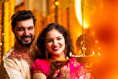 Diwali 'de Pirinç Yağı Samai, Geleneksel Kurta' da Hintli Genç Adam ve Kadın Gülümseyen Sari Dekoratif Festival Lambası Gece Samimi Etnik Ev Ayarları 'nda