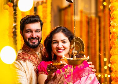 Diwali 'de Pirinç Yağı Samai, Geleneksel Kurta' da Hintli Genç Adam ve Kadın Gülümseyen Sari Dekoratif Festival Lambası Gece Samimi Etnik Ev Ayarları 'nda