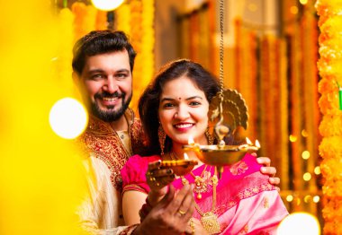 Diwali 'de Pirinç Yağı Samai, Geleneksel Kurta' da Hintli Genç Adam ve Kadın Gülümseyen Sari Dekoratif Festival Lambası Gece Samimi Etnik Ev Ayarları 'nda