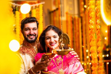 Diwali 'de Pirinç Yağı Samai, Geleneksel Kurta' da Hintli Genç Adam ve Kadın Gülümseyen Sari Dekoratif Festival Lambası Gece Samimi Etnik Ev Ayarları 'nda