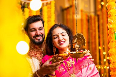 Diwali 'de Pirinç Yağı Samai, Geleneksel Kurta' da Hintli Genç Adam ve Kadın Gülümseyen Sari Dekoratif Festival Lambası Gece Samimi Etnik Ev Ayarları 'nda