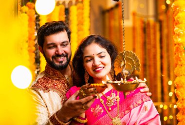 Diwali 'de Pirinç Yağı Samai, Geleneksel Kurta' da Hintli Genç Adam ve Kadın Gülümseyen Sari Dekoratif Festival Lambası Gece Samimi Etnik Ev Ayarları 'nda