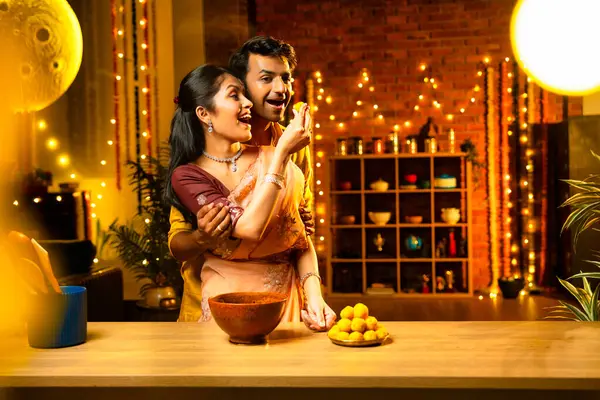 Hint çifti Diwali 'de süslü mutfakta laddu yapıyor. Işıklar ve çiçek çelenkleriyle dolu, neşe içinde geleneksel laddoo' yu hazırlıyor, sergiliyor ya da birlikte yiyor.