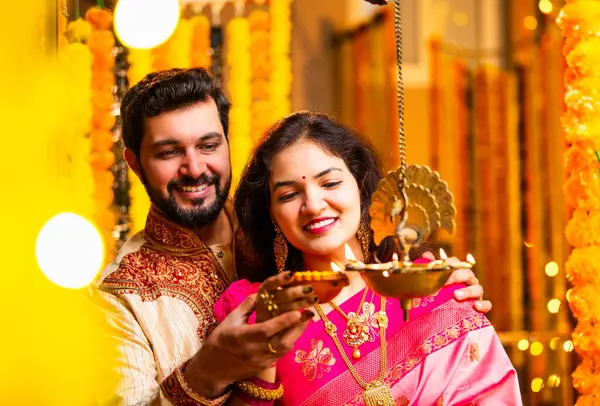 Diwali 'de Pirinç Yağı Samai, Geleneksel Kurta' da Hintli Genç Adam ve Kadın Gülümseyen Sari Dekoratif Festival Lambası Gece Samimi Etnik Ev Ayarları 'nda