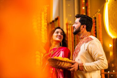 Marigold Garland ile Diwali İçin Dekorasyon, Geleneksel Etnik Giyimli Mutlu Hintli Genç Evli Çift, Hindu Festivali Kutlamaları sırasında İçerde Çiçek Dekorasyonu Yapıyor