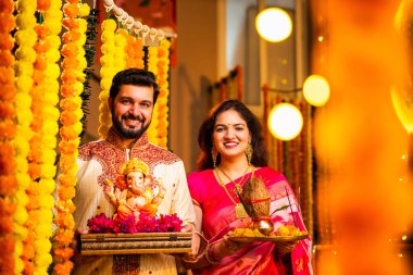 Ganesh Idol ve Joy 'u karşılayan Hintli çift Ganesh Idol, Ganpati Bappa Idol, Puja Thali, Ganesh Festivali Kutlamaları sırasında gülümseyen ve Bappa Morya' yı tezahürat yapan