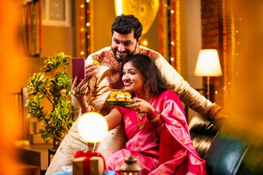 Diwali Video Call 'dan dilek diliyor. Geleneksel Etnik Giyimli Hintli genç çift Diwali Festivali 'nde Işık ve Şölen Dekorasyonu' nda Akrabaları bağlamak için akıllı telefonu kullanıyor