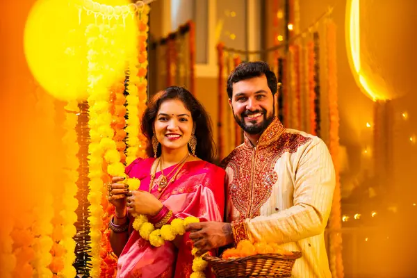 Marigold Garland ile Diwali İçin Dekorasyon, Geleneksel Etnik Giyimli Mutlu Hintli Genç Evli Çift, Hindu Festivali Kutlamaları sırasında İçerde Çiçek Dekorasyonu Yapıyor
