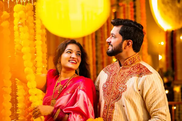 Marigold Garland ile Diwali İçin Dekorasyon, Geleneksel Etnik Giyimli Mutlu Hintli Genç Evli Çift, Hindu Festivali Kutlamaları sırasında İçerde Çiçek Dekorasyonu Yapıyor