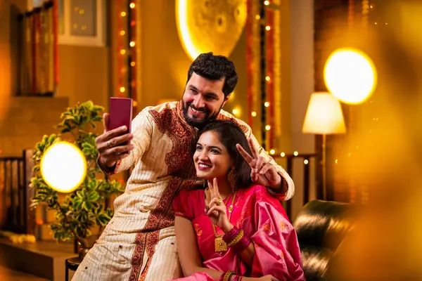 Diwali Video Call 'dan dilek diliyor. Geleneksel Etnik Giyimli Hintli genç çift Diwali Festivali 'nde Işık ve Şölen Dekorasyonu' nda Akrabaları bağlamak için akıllı telefonu kullanıyor