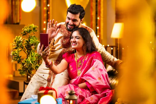 Diwali Video Call 'dan dilek diliyor. Geleneksel Etnik Giyimli Hintli genç çift Diwali Festivali 'nde Işık ve Şölen Dekorasyonu' nda Akrabaları bağlamak için akıllı telefonu kullanıyor
