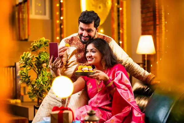 Diwali Video Call 'dan dilek diliyor. Geleneksel Etnik Giyimli Hintli genç çift Diwali Festivali 'nde Işık ve Şölen Dekorasyonu' nda Akrabaları bağlamak için akıllı telefonu kullanıyor