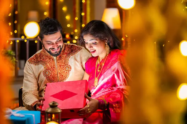 Açılış Parlayan Hediye Kutusu, Tatlılar ve Hediyelerle çevrili, Evde Diwali Festivali 'ni kutlayan Hintli genç çift, Kutudan çıkan parıltıyla şaşırdılar.