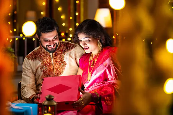 Açılış Parlayan Hediye Kutusu, Tatlılar ve Hediyelerle çevrili, Evde Diwali Festivali 'ni kutlayan Hintli genç çift, Kutudan çıkan parıltıyla şaşırdılar.