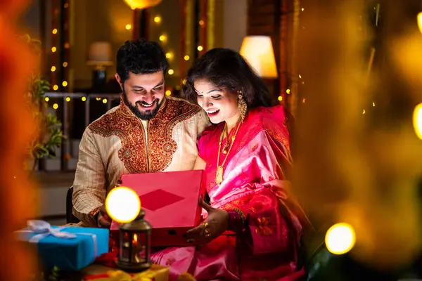 Açılış Parlayan Hediye Kutusu, Tatlılar ve Hediyelerle çevrili, Evde Diwali Festivali 'ni kutlayan Hintli genç çift, Kutudan çıkan parıltıyla şaşırdılar.