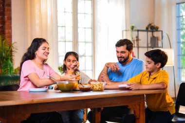 Aile evde panipuri atıştırmalıkları yiyor, Hintli baba, anne, oğul kız rahat oturma odasındaki yemek masasında golgappanın tadını çıkarırken sohbet ediyor, gülüyor ve kaliteli zaman geçiriyor.