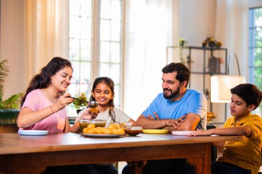 Aile evde panipuri atıştırmalıkları yiyor, Hintli baba, anne, oğul kız rahat oturma odasındaki yemek masasında golgappanın tadını çıkarırken sohbet ediyor, gülüyor ve kaliteli zaman geçiriyor.