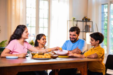 Aile evde panipuri atıştırmalıkları yiyor, Hintli baba, anne, oğul kız rahat oturma odasındaki yemek masasında golgappanın tadını çıkarırken sohbet ediyor, gülüyor ve kaliteli zaman geçiriyor.