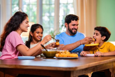 Aile evde panipuri atıştırmalıkları yiyor, Hintli baba, anne, oğul kız rahat oturma odasındaki yemek masasında golgappanın tadını çıkarırken sohbet ediyor, gülüyor ve kaliteli zaman geçiriyor.