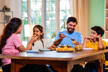 Aile evde panipuri atıştırmalıkları yiyor, Hintli baba, anne, oğul kız rahat oturma odasındaki yemek masasında golgappanın tadını çıkarırken sohbet ediyor, gülüyor ve kaliteli zaman geçiriyor.