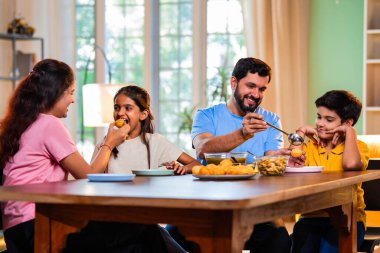 Aile evde panipuri atıştırmalıkları yiyor, Hintli baba, anne, oğul kız rahat oturma odasındaki yemek masasında golgappanın tadını çıkarırken sohbet ediyor, gülüyor ve kaliteli zaman geçiriyor.