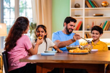 Aile evde panipuri atıştırmalıkları yiyor, Hintli baba, anne, oğul kız rahat oturma odasındaki yemek masasında golgappanın tadını çıkarırken sohbet ediyor, gülüyor ve kaliteli zaman geçiriyor.
