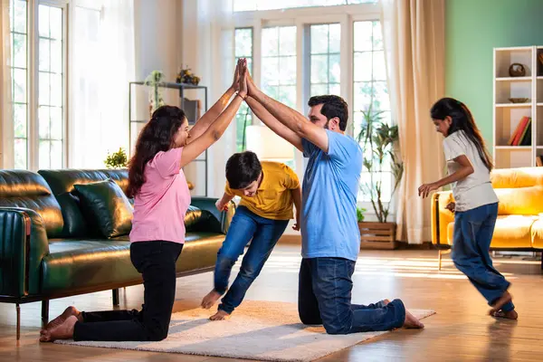 Aile Londra Köprüsü oyunu oynuyor. Modern evlerin içine düşüyorlar. Hintli anne, baba, oğul, kız.