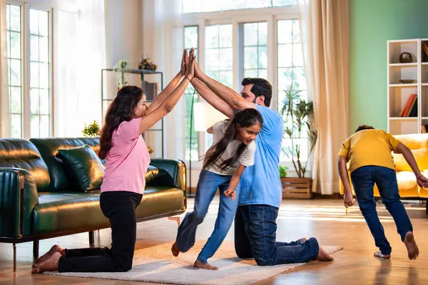 Aile Londra Köprüsü oyunu oynuyor. Modern evlerin içine düşüyorlar. Hintli anne, baba, oğul, kız.