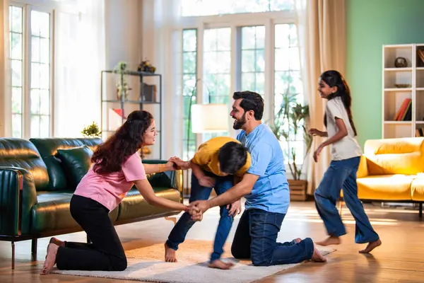 Aile Londra Köprüsü oyunu oynuyor. Modern evlerin içine düşüyorlar. Hintli anne, baba, oğul, kız.