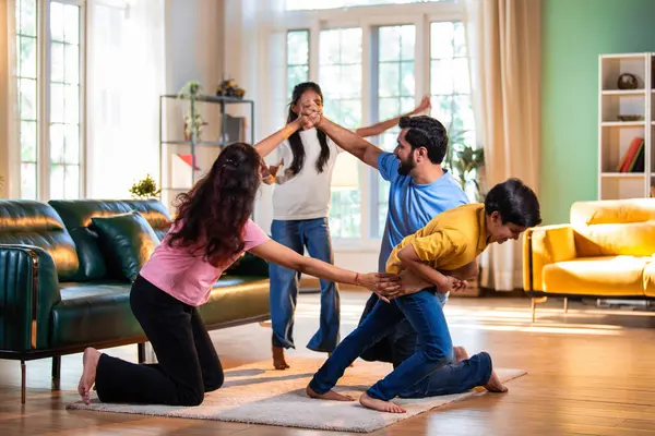Aile Londra Köprüsü oyunu oynuyor. Modern evlerin içine düşüyorlar. Hintli anne, baba, oğul, kız.