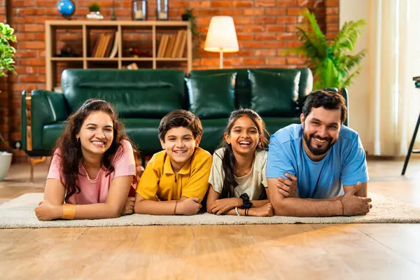 Aile çene üzerinde mutlu bir şekilde uzanmış, Hintli baba, anne, oğul, modern, müsrif oturma odasında kameraya bakıyor, evde birlikte rahatlıyor, bağ kuruyor ve eğleniyoruz.