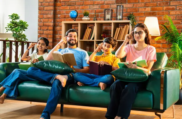 Aile kitap tanıtımını evde rahat bir kanepede otururken yapıyor. Çocuklu Asyalı genç bir çift okuma alışkanlığı geliştirmenin önemini anlatıyor. Zeka ve iç mekanda gelişim.