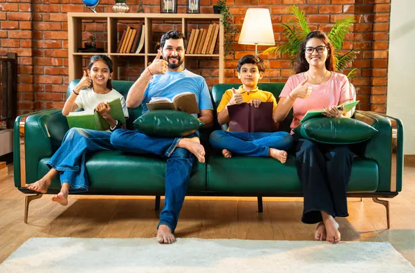 Aile kitap tanıtımını evde rahat bir kanepede otururken yapıyor. Çocuklu Asyalı genç bir çift okuma alışkanlığı geliştirmenin önemini anlatıyor. Zeka ve iç mekanda gelişim.